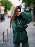 Person wearing a green hoodie on a street with blurred background
