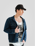 Person wearing a denim jacket and black cap on a plain background