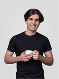 Man holding a white mug against a plain background